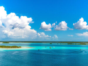 Laguna de Bacalar com águas azul-turquesa e tons cristalinos, rodeada por natureza tropical.