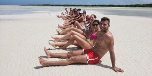 Pessoas a posar em Punta Mosquito, com águas rasas e paisagem paradisíaca ao fundo.