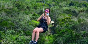 Tirolesa (zipline) sobre a selva maia na Riviera Maya, atravessando a copa das árvores com vistas da paisagem tropical.