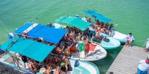 Bandeira de Portugal numa lancha com um grande grupo de pessoas em Holbox, sobre águas turquesa do Caribe.