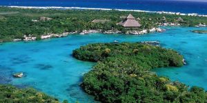 Vista aérea de Xel-Há, com lagoa cristalina, vegetação tropical e mar do Caribe ao redor.