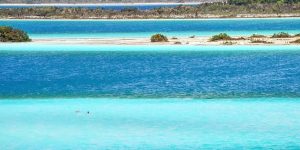 Vista da Lagoa de Bacalar com suas águas em diferentes tons de azul, vegetação ao redor e uma atmosfera tropical tranquila.