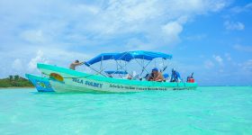 Lancha na zona de El Cielo Cozumel, sobre águas rasas e cristalinas do Caribe, rodeada por tons azul-turquesa.